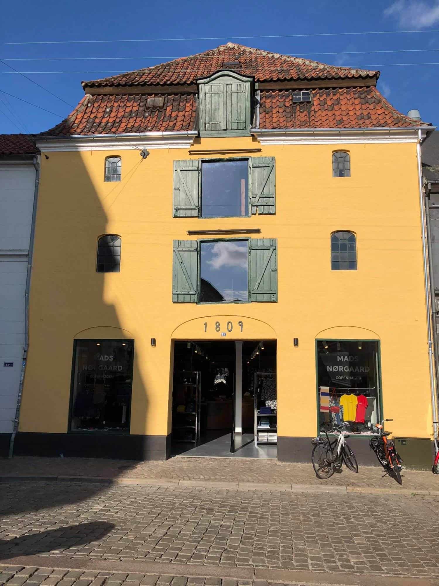 Hus med gul facade og grønne vinduesrammer i centrum.