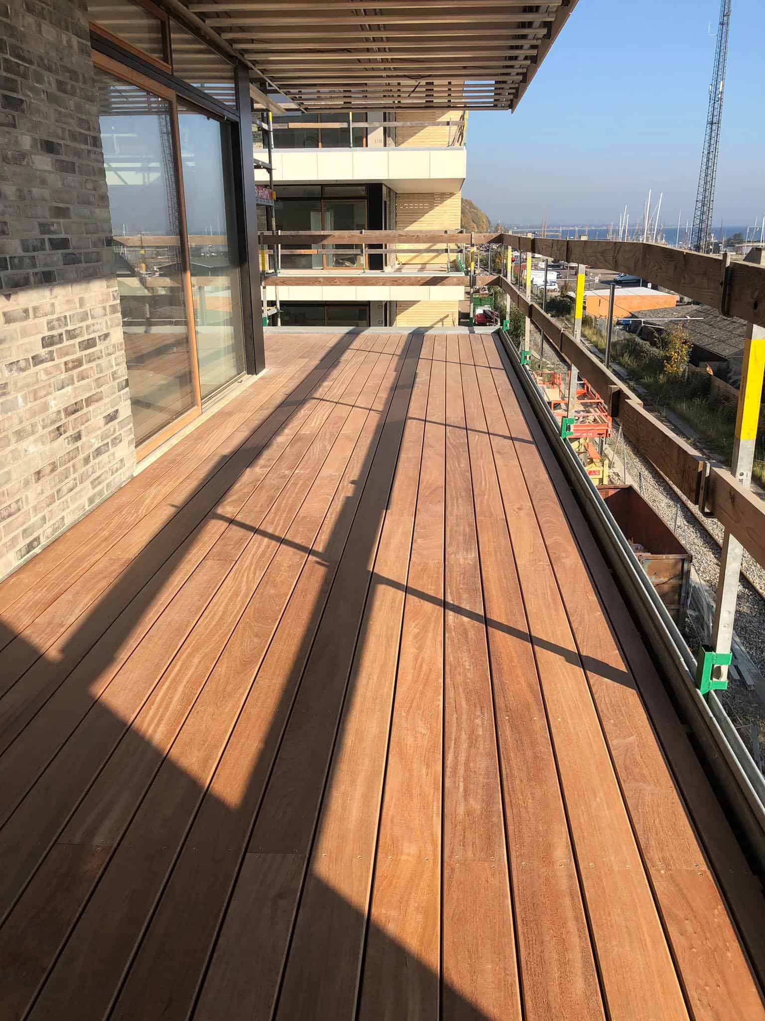 Udendørs træterrasse på en nybygget bolig med udsigt over byen.