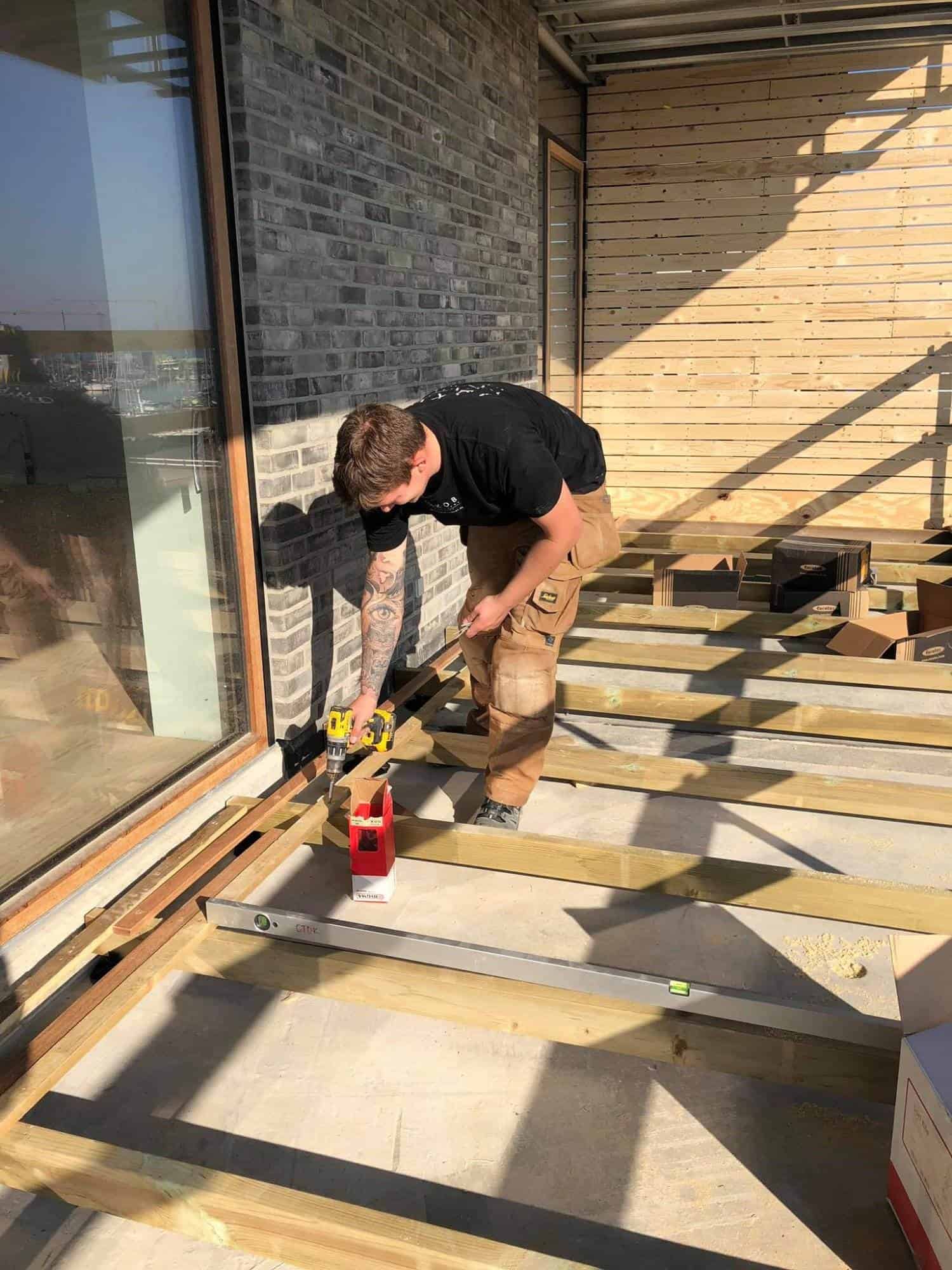 Tømrer arbejder på at bygge en terrasse udendørs.