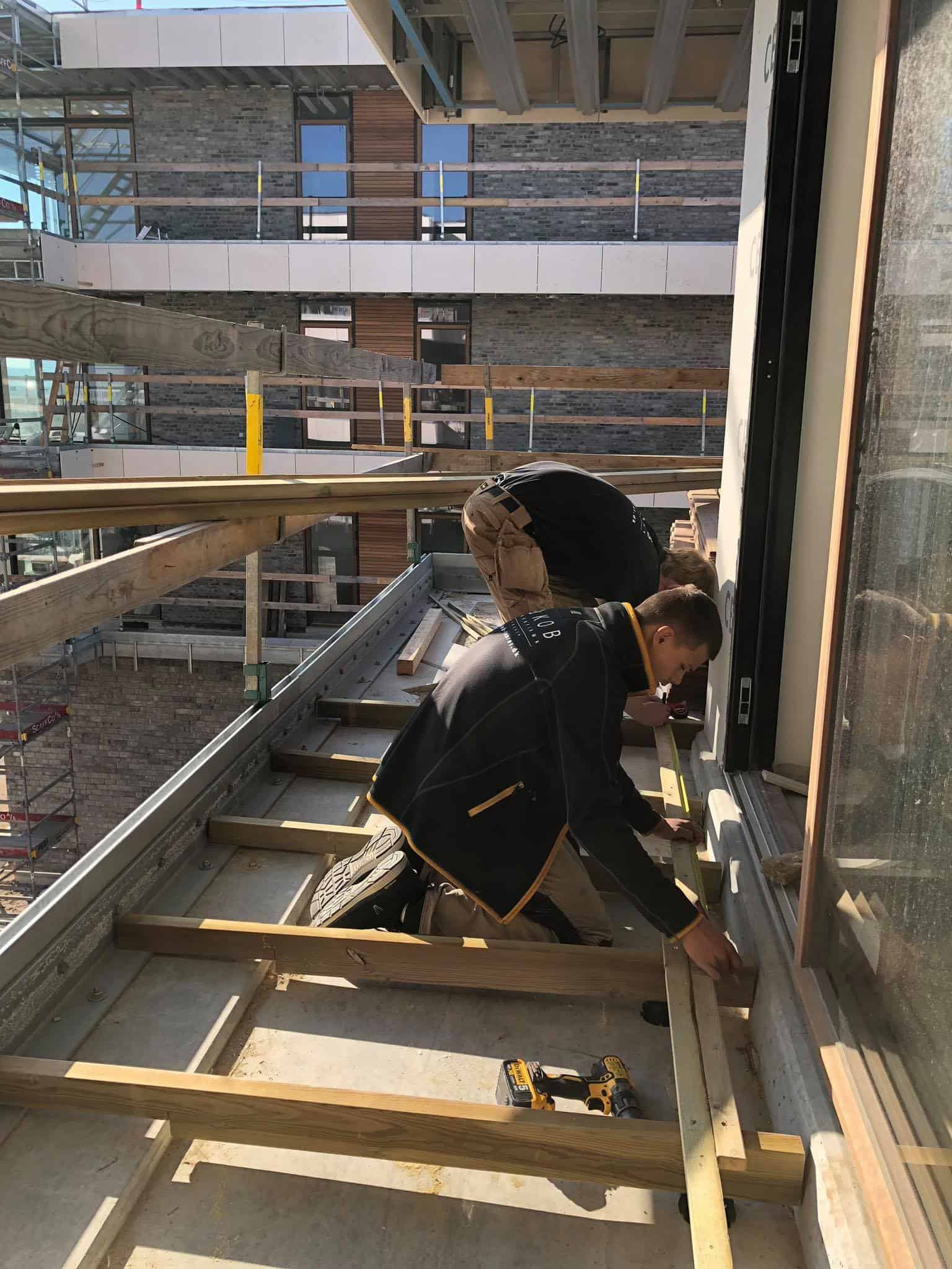 Tømrer arbejder på en byggeplads med fokus på vinduesinstallation.