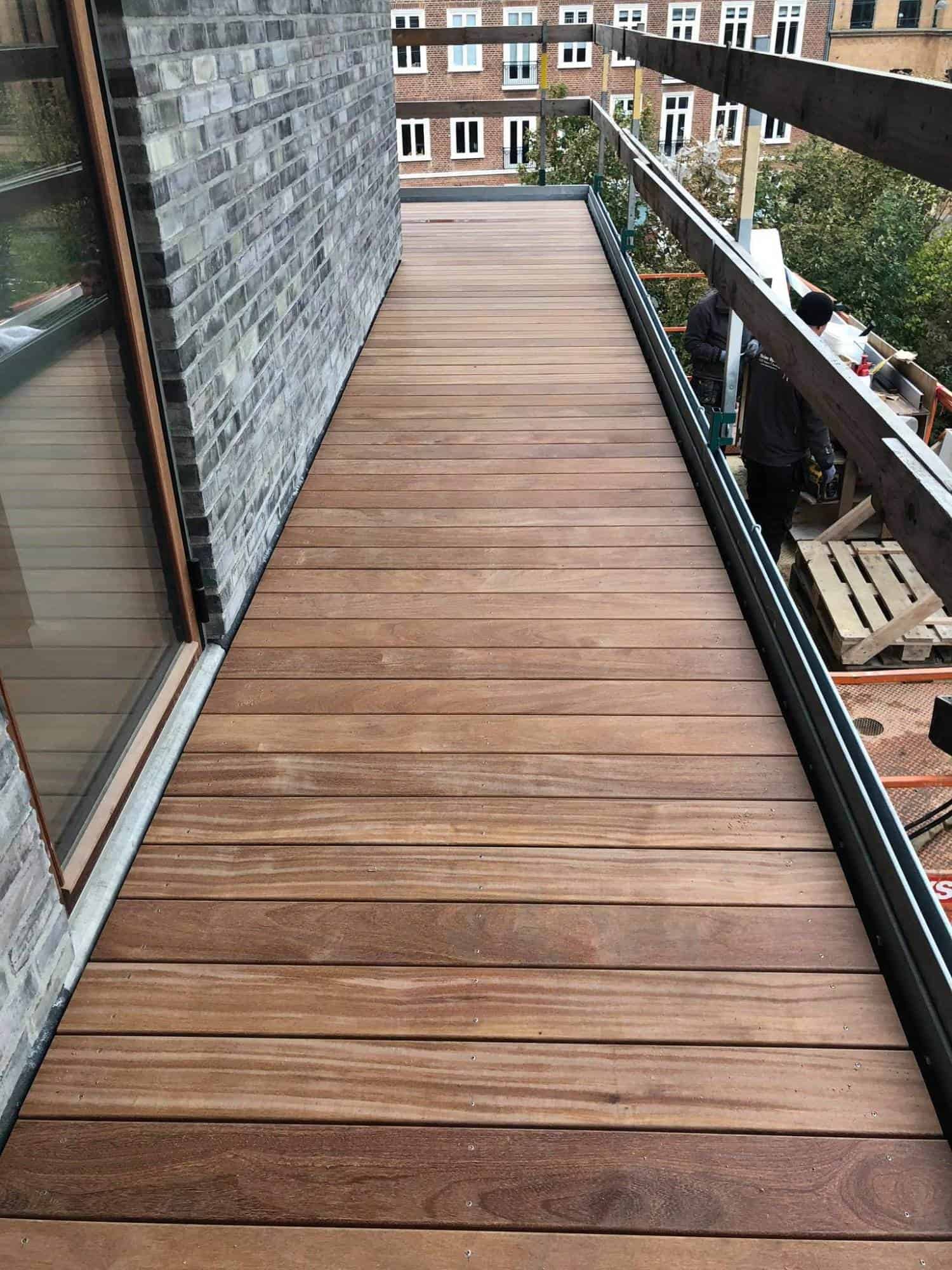 Træterrasse på lejlighed med glasdør og byudsigt.