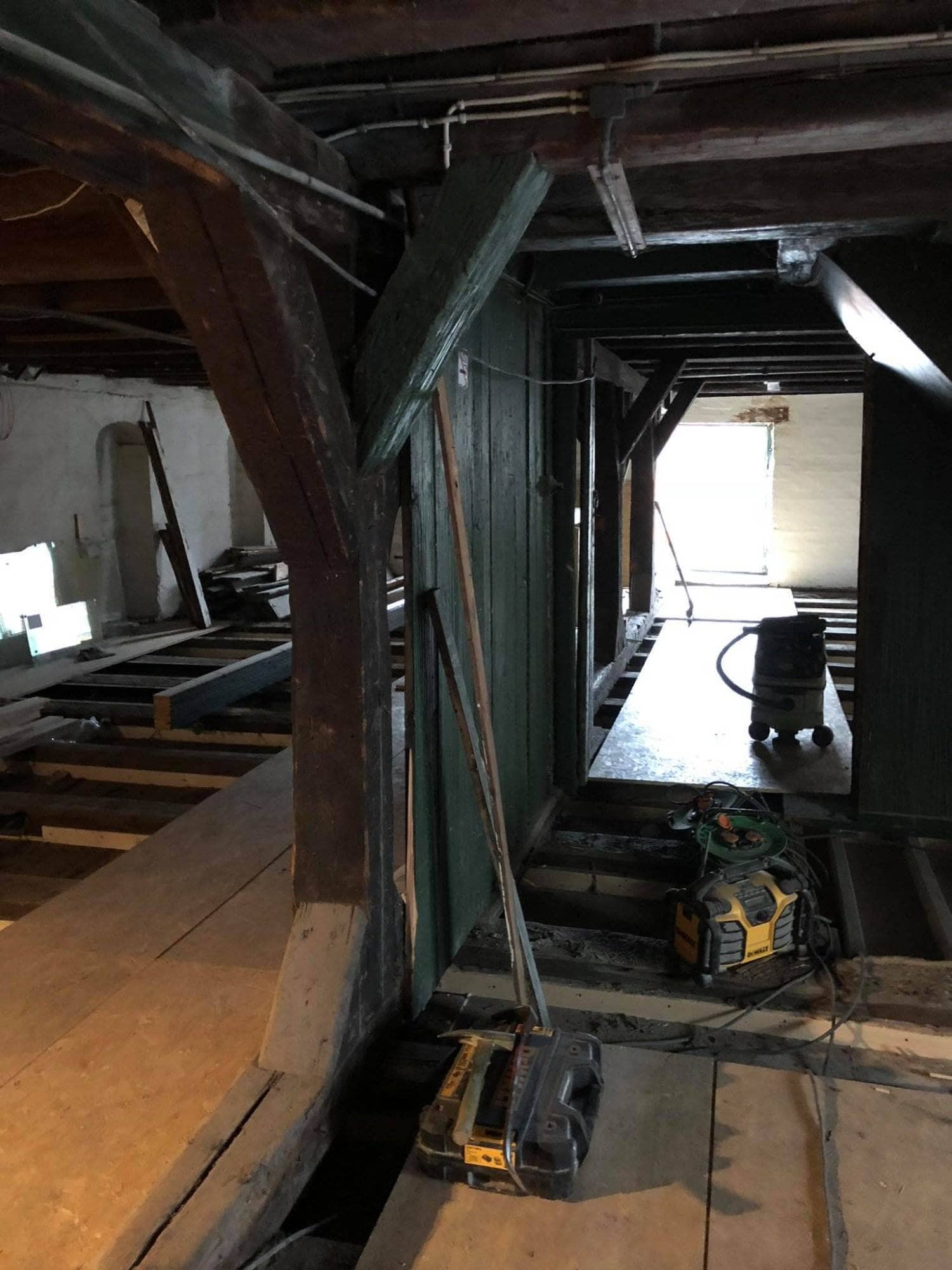 Tømrerarbejde i en ældre bygning med synlige træbjælker og renoveringsmaterialer.