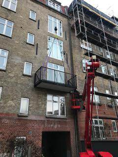 Udendørs byggeri af lejlighed i højhus med balkon og stillads.