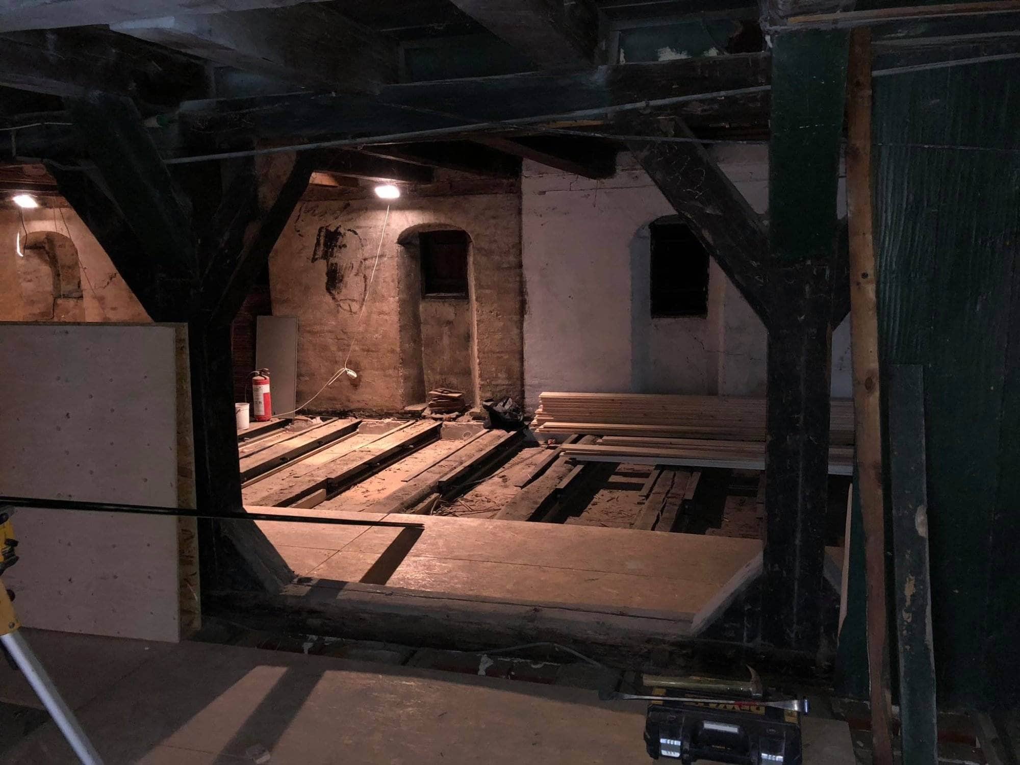 Tømrerarbejde i en gammel, charmerende bygning med synlige træbjælker og renoveringsmaterialer.