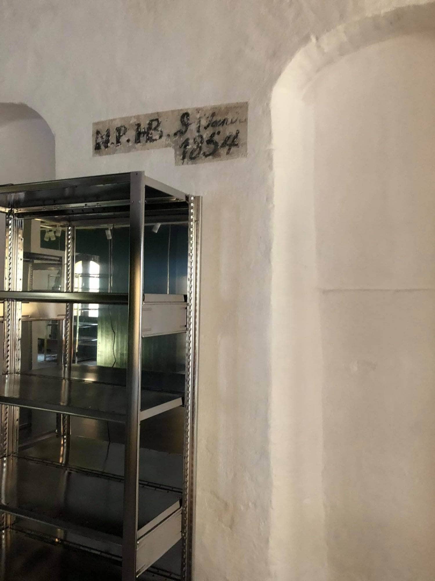 Vægmonteret hylde i et byggeri, klar til installation, med synlige metalrammer og vægskruer.