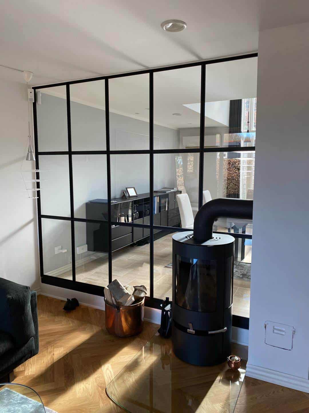 Moderne glasvæg med sort ramme til opdeling af rum.