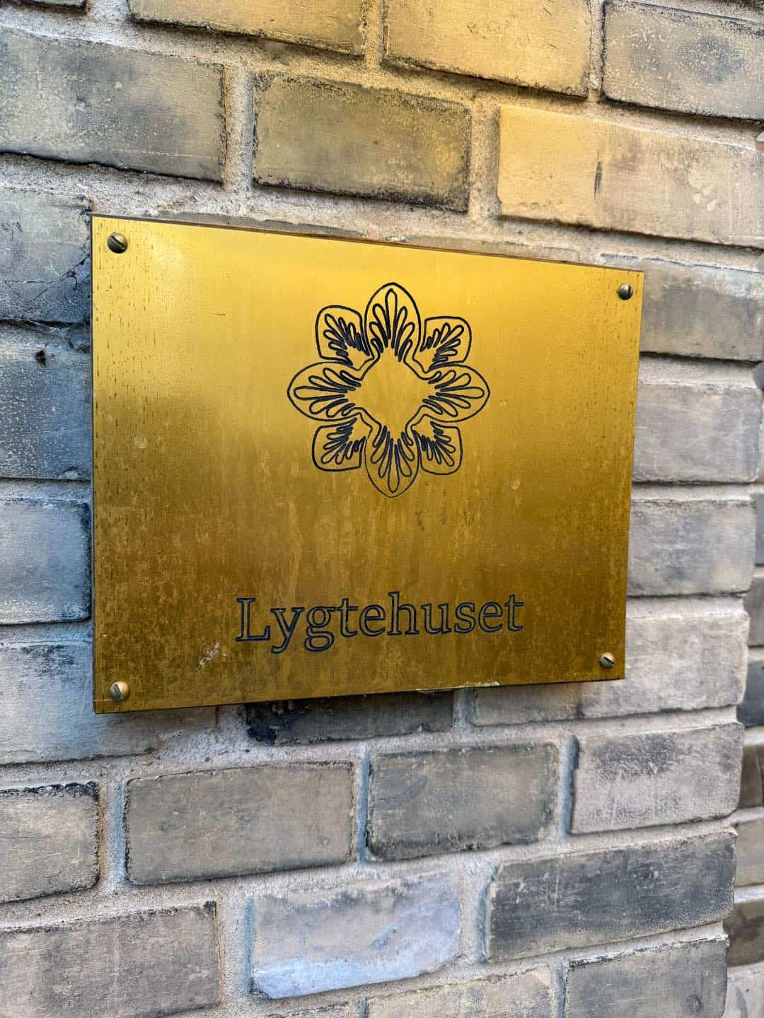 Guldskilt med Lygtehuset logo på murstensvæg.