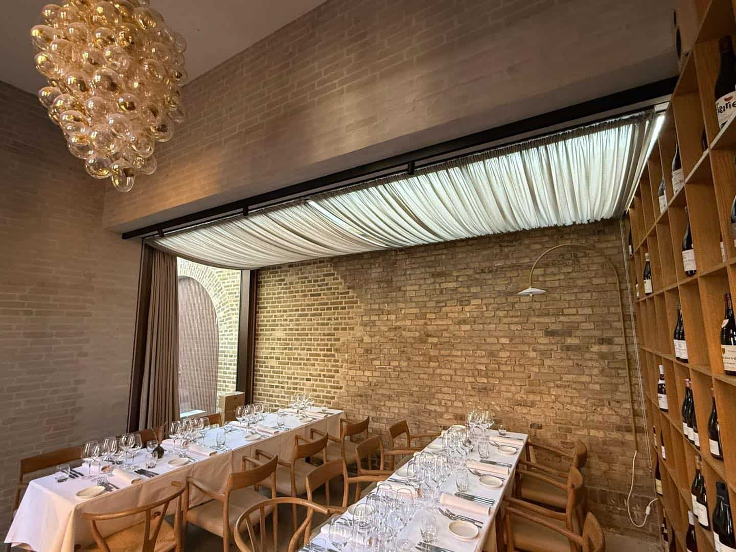 Indendørs restaurant med elegant gardin og brændt murstensvæg.