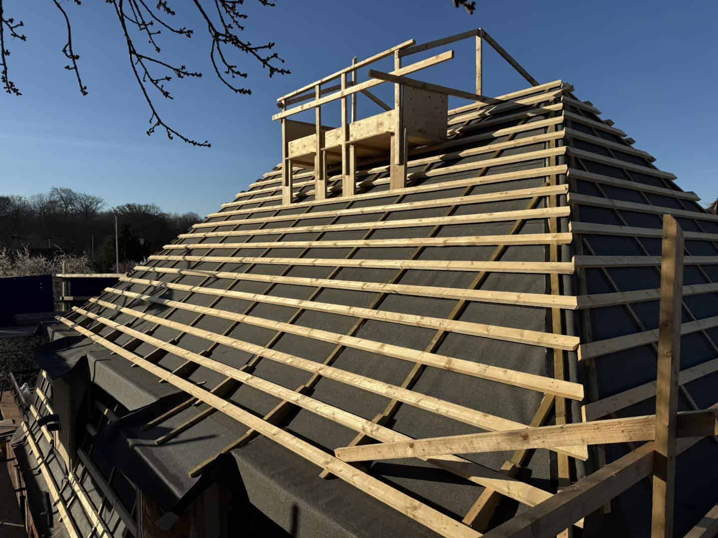 Tagkonstruktion under opbygning med træspær og stillads.