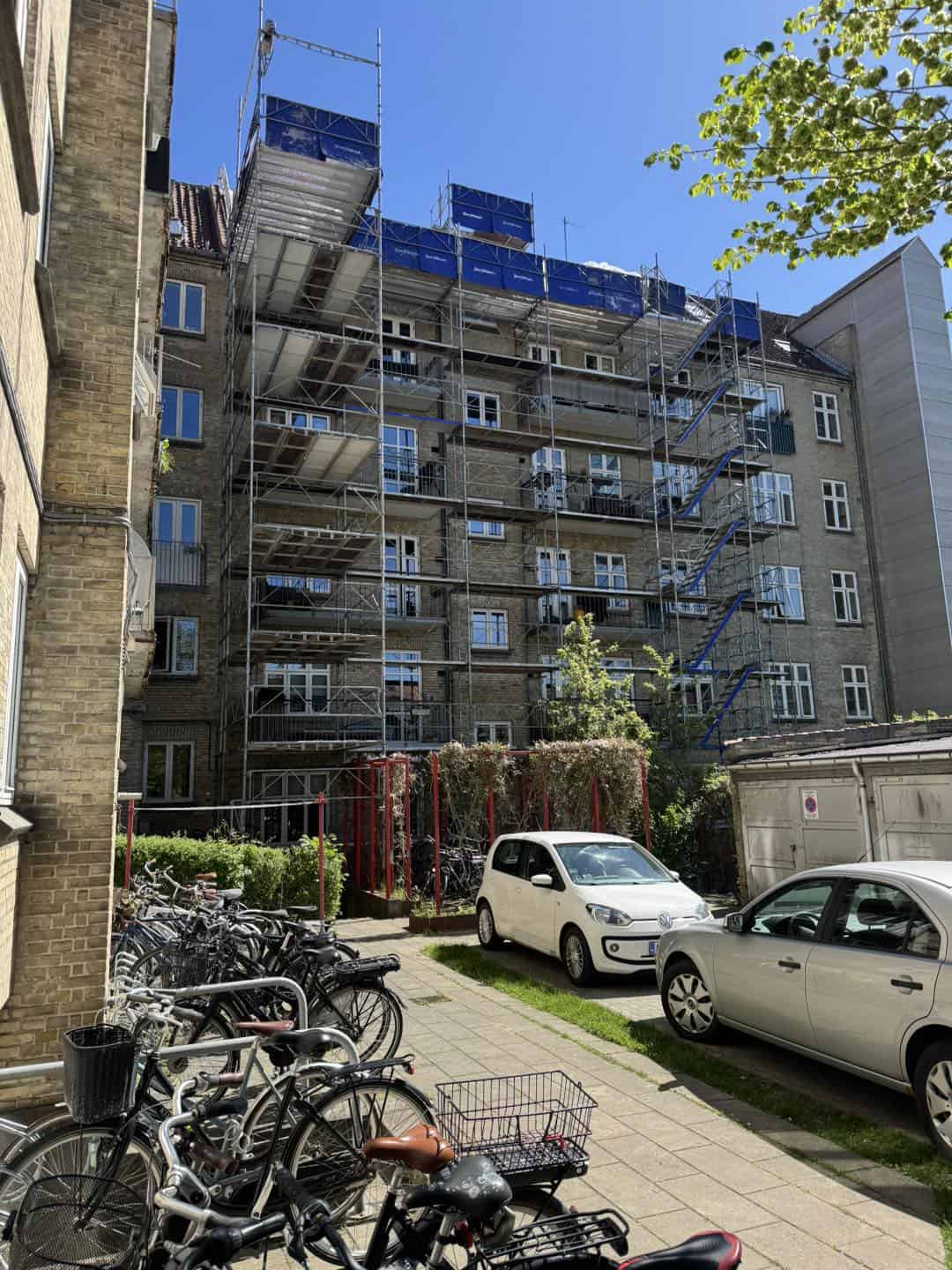 Byggeri af lejlighedskompleks med stilladser og moderne facade i centrum af byen.