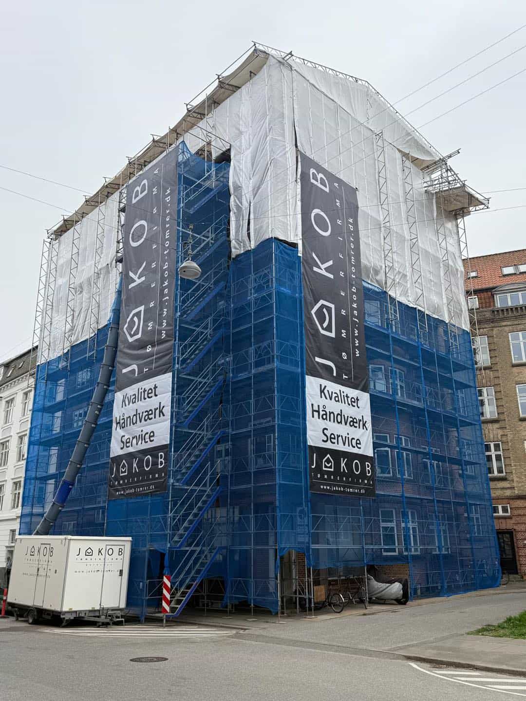 Bygningsprojekt under opførelse med facadebeklædning i blå og hvidt.