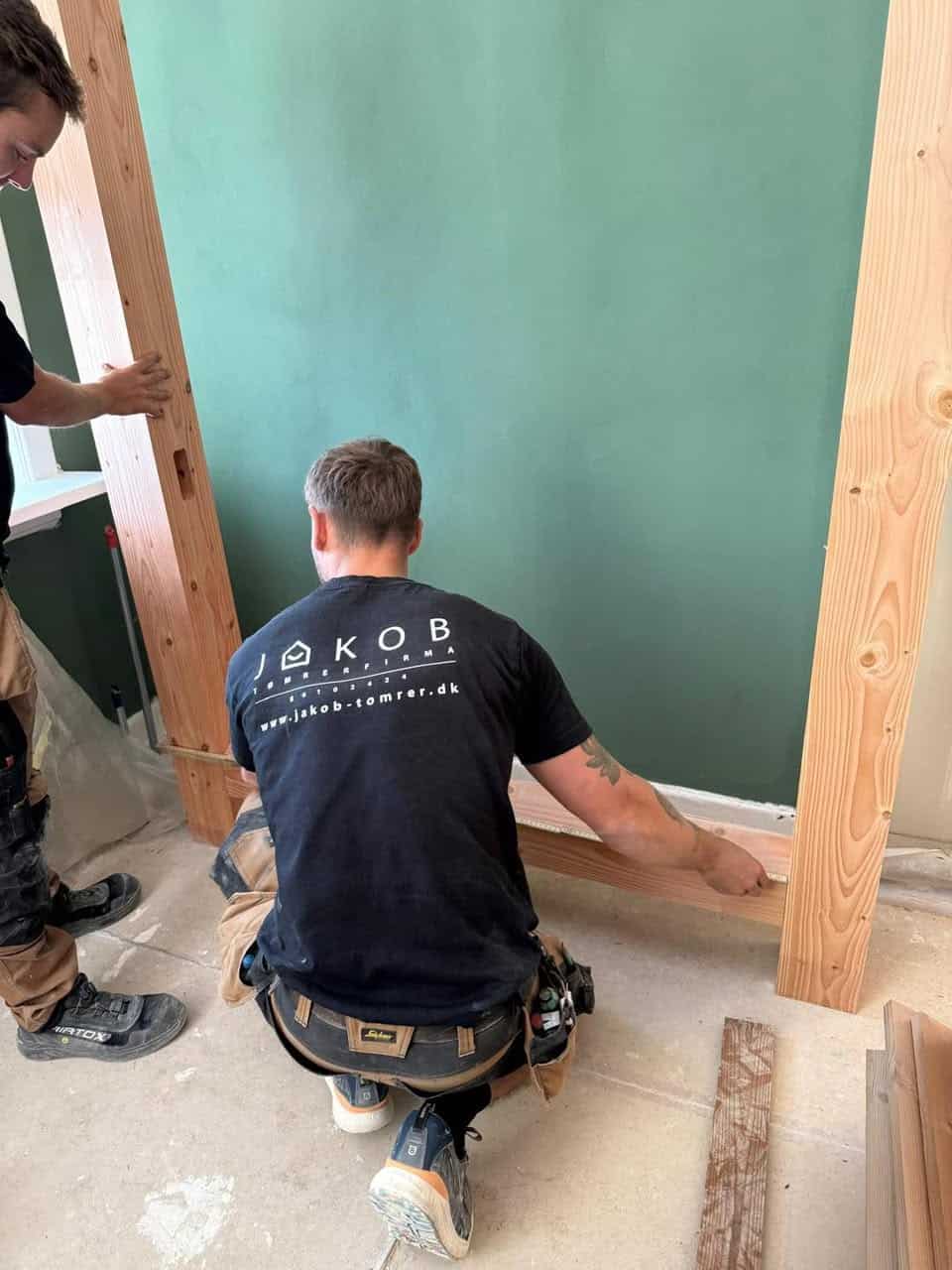 Tømrer der arbejder på væg med fokus på arkitektur og præcision.