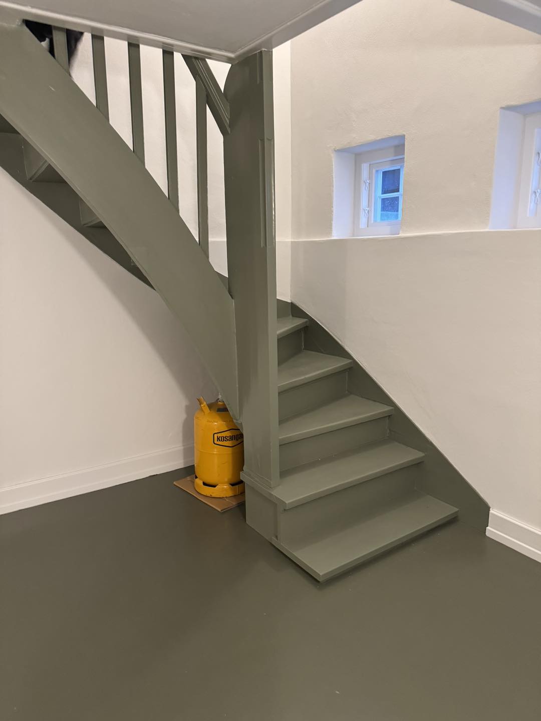 Trappe i gråt træ med elegant design, der fremhæver arkitekturens respekt og fokus på detaljerne.