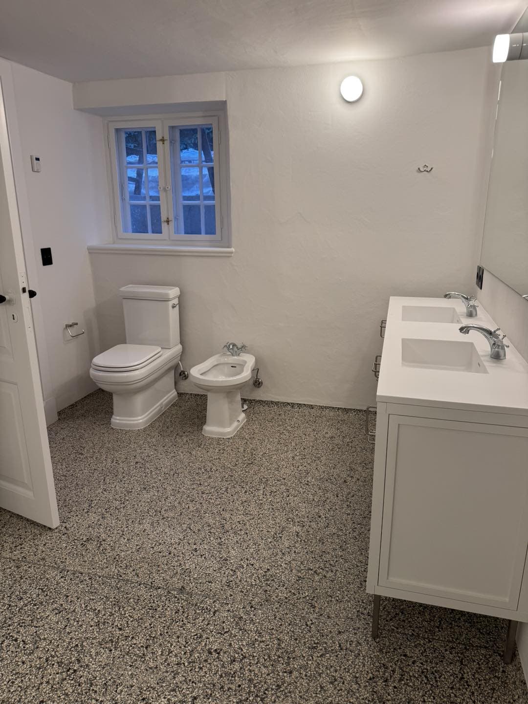 Badeværelse med elegant vask, toilet og vindue, der fremhæver arkitekturens respekt og detaljernes b.