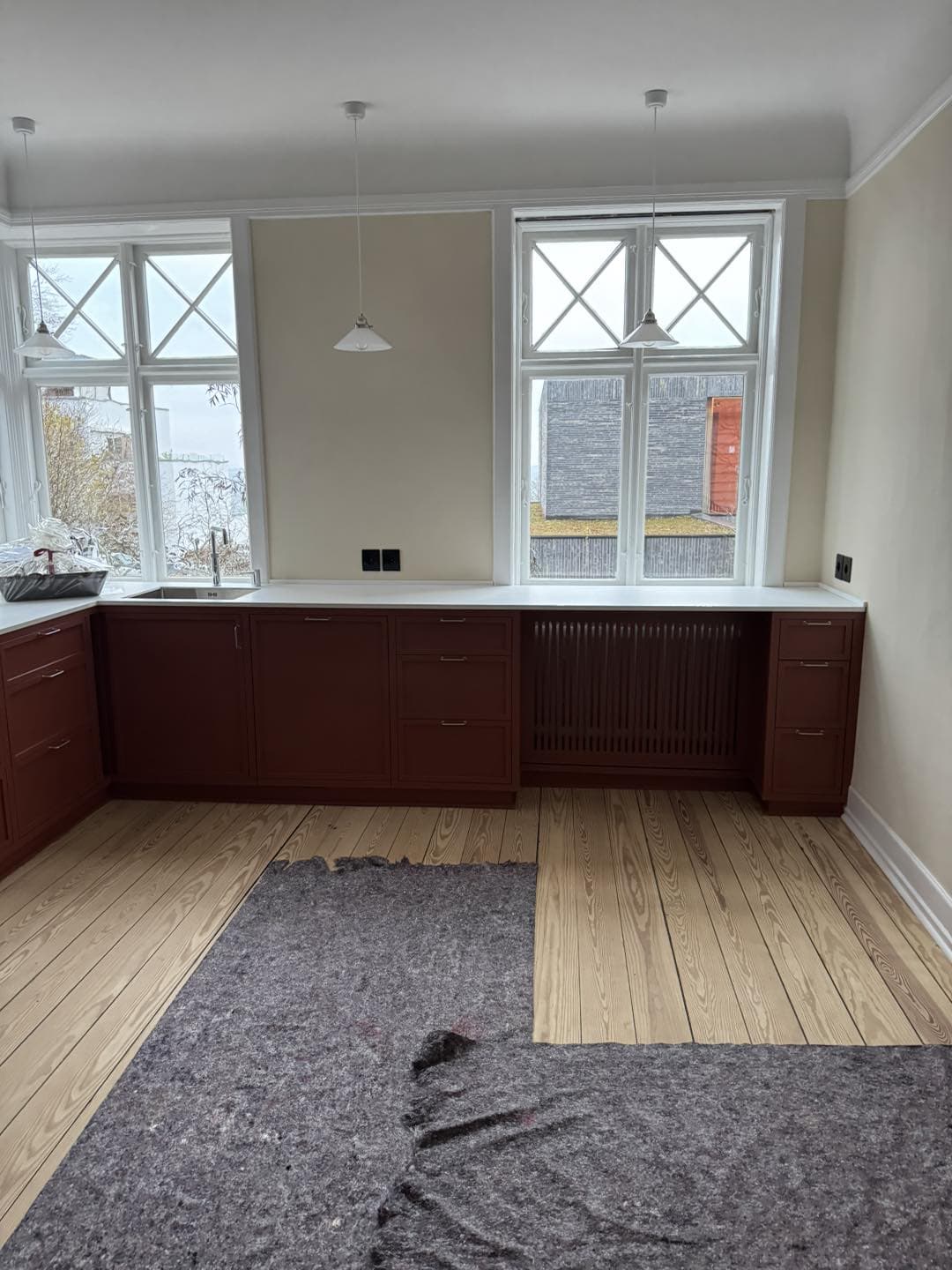 Køkken med specialfremstillet træbordplade og store vinduer.