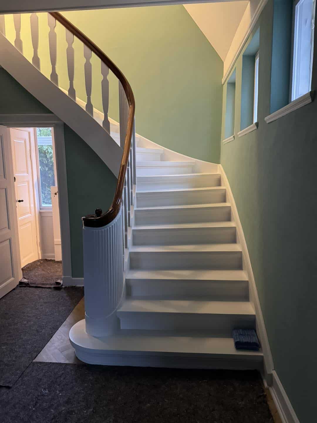 Håndlavet trappe i træ med elegant trægelænder, der fremhæver arkitekturen og detaljerne i hjemmet.