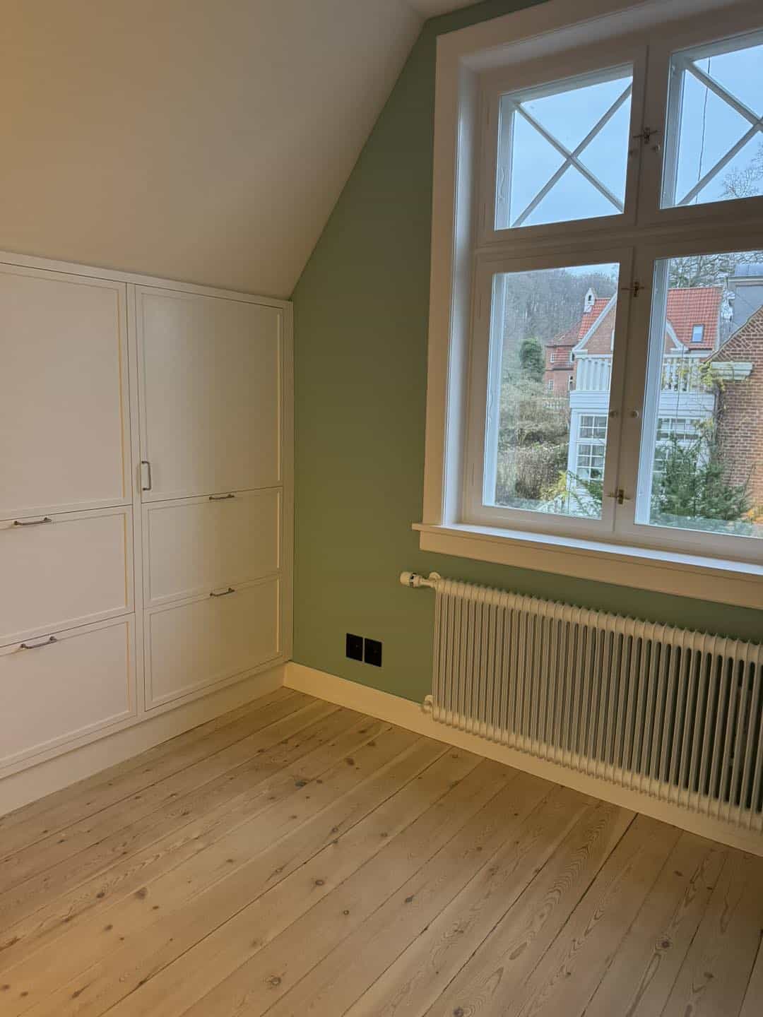 Billede af et lyst, moderne værelse med store vinduer og smukke trædetaljer.