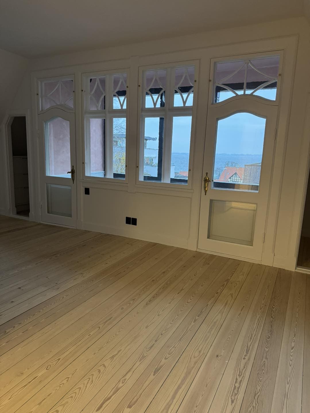 Nyrenoverede vinduer med detaljeret træramme og udsigt over havet.