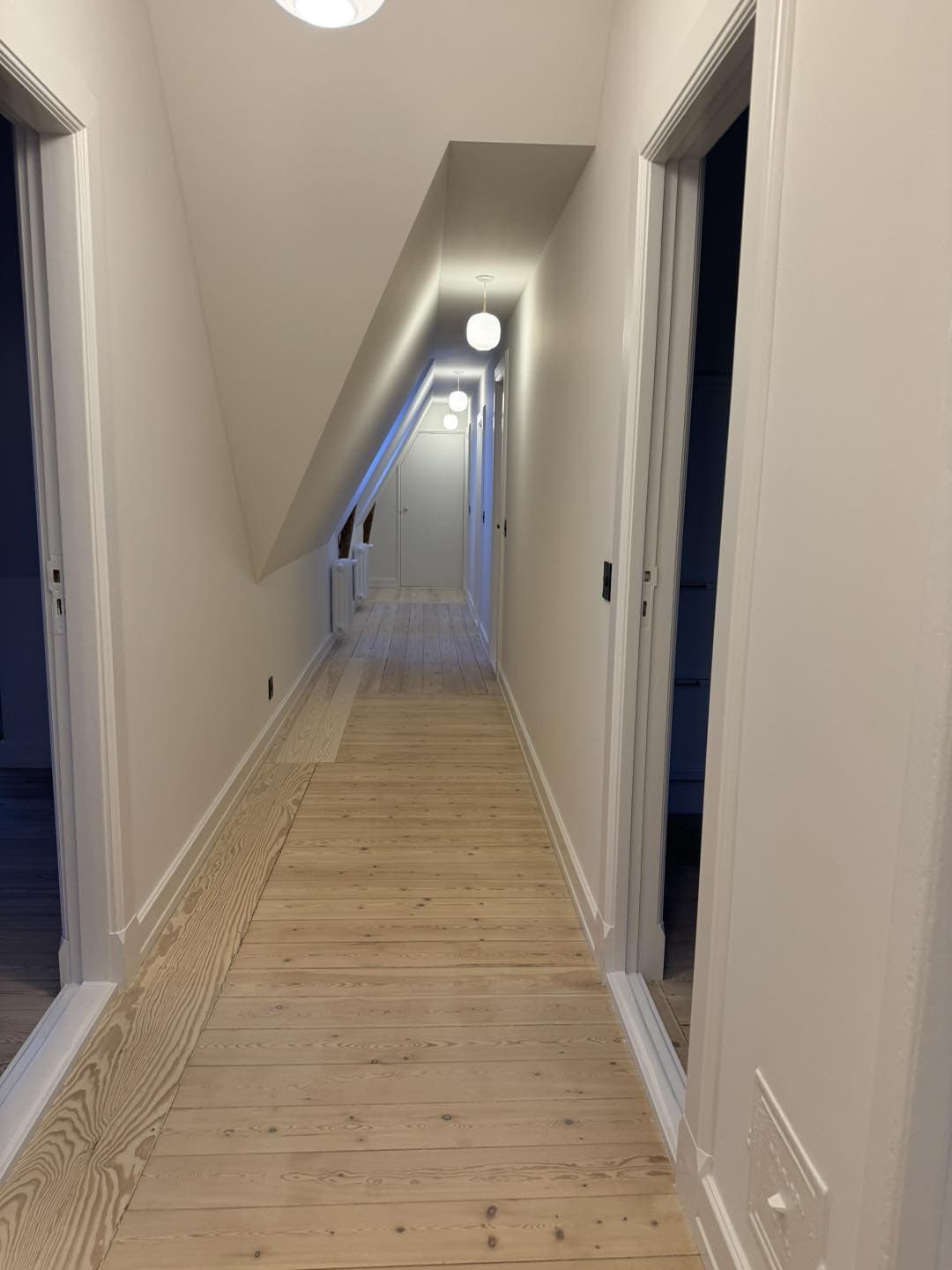 Elegant, lyst trappegang med trægulv og moderne belysning.