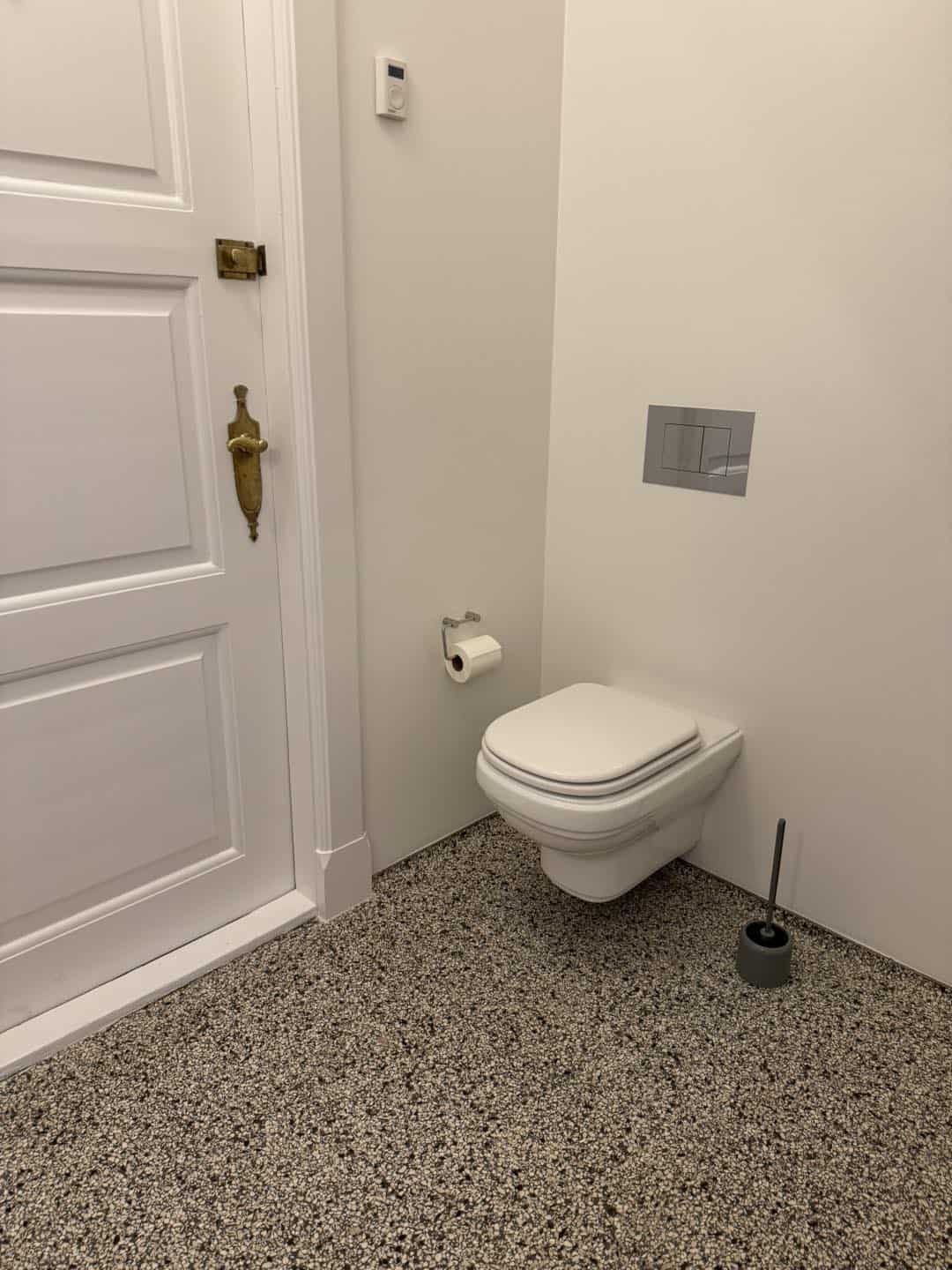 Moderne hvidt toilet i et enkelt badeværelse med fokus på arkitektur og detaljer.