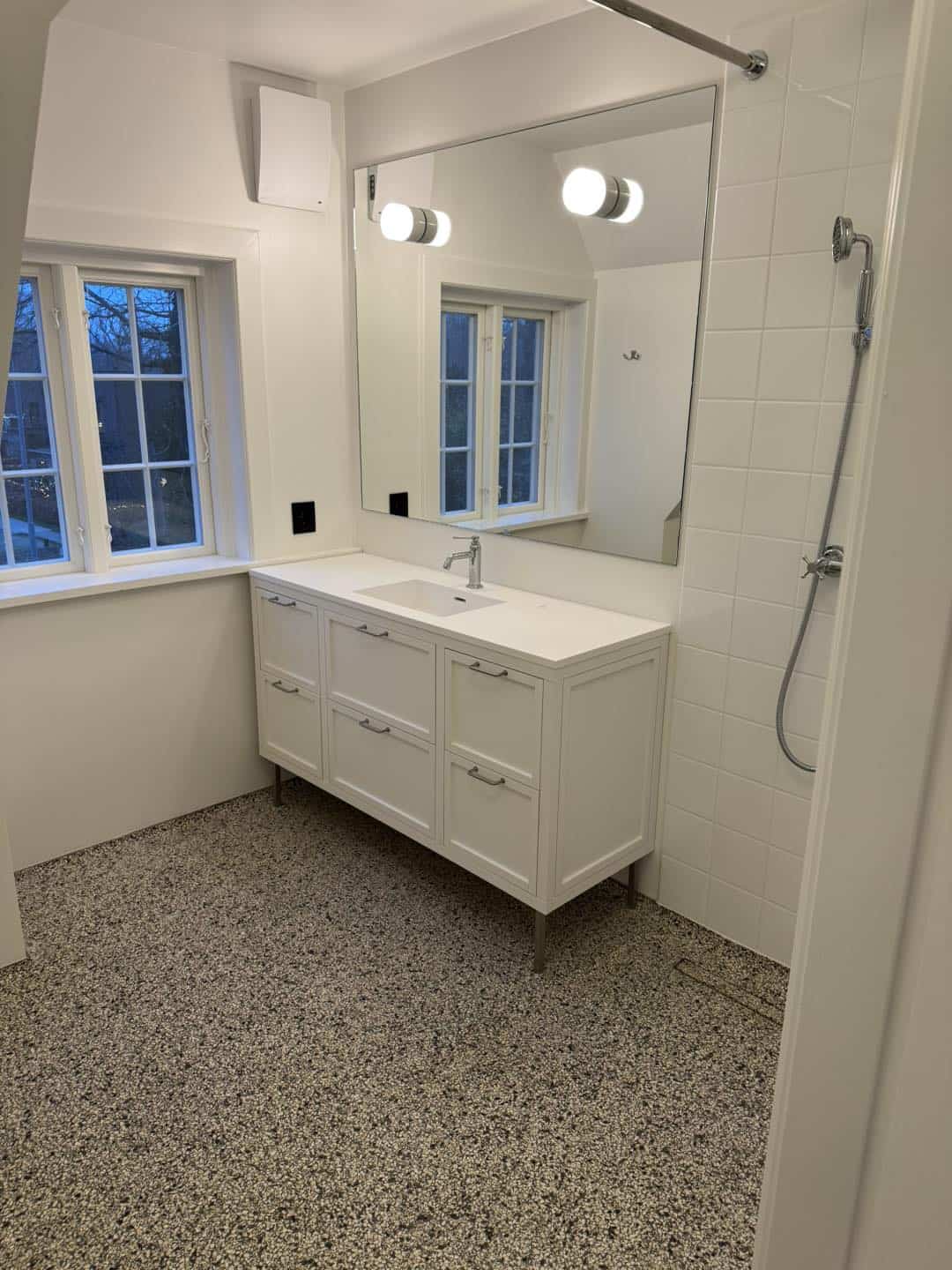 Badeværelse med elegant spejl, moderne belysning og funktionelt inventar.