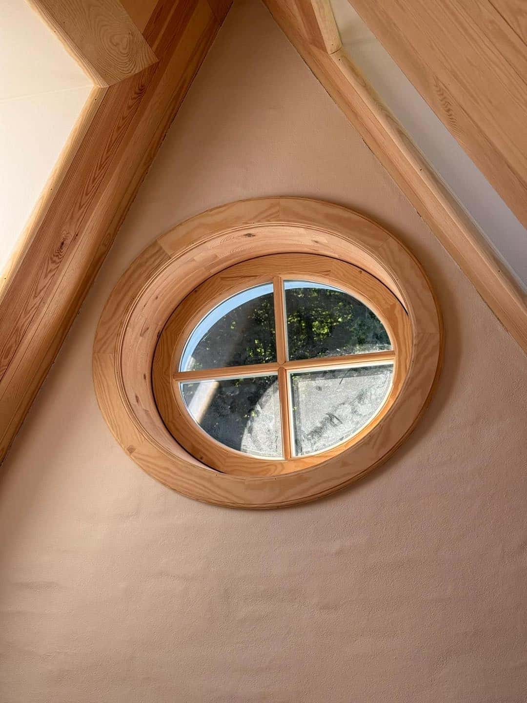 Unikt rundt vindue i træ, der fremhæver arkitektonisk finesse og håndværk.