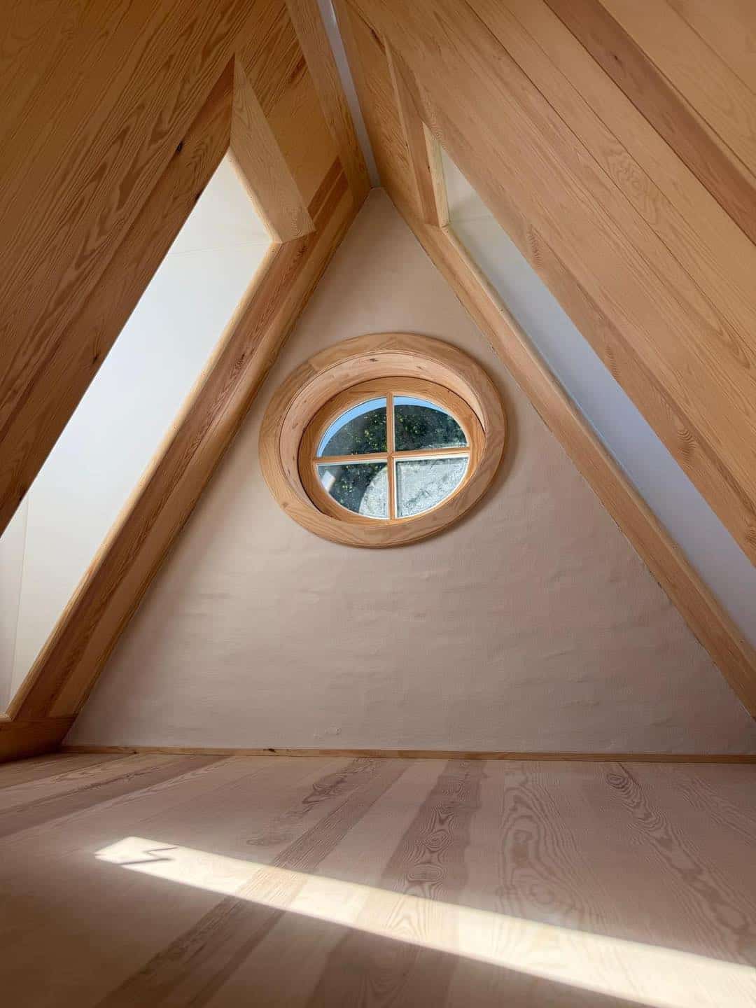 Loft med rund vindue og trædetaljer.
