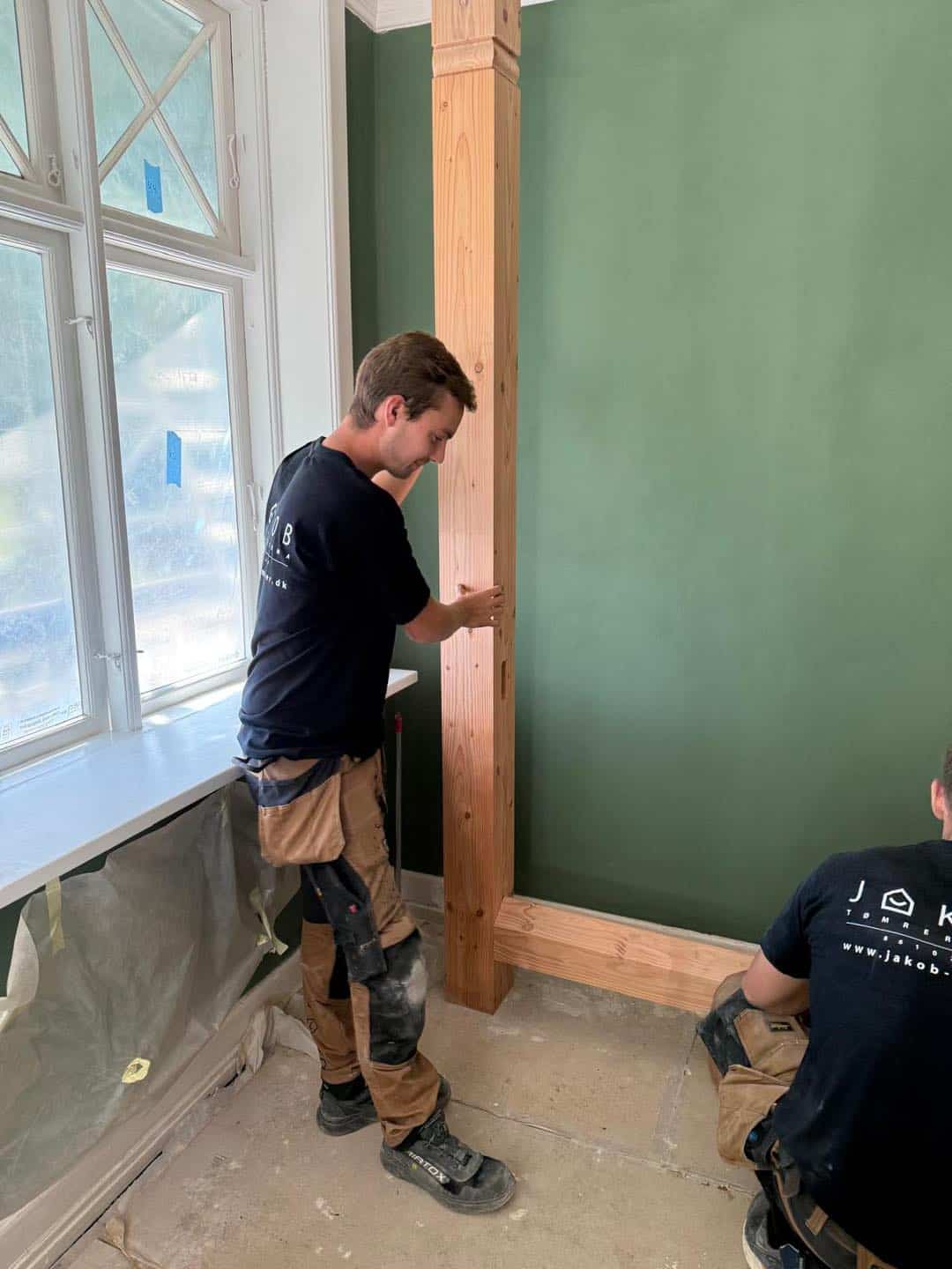 Tømrer, der arbejder på indendørs træværk i et moderne hjem.