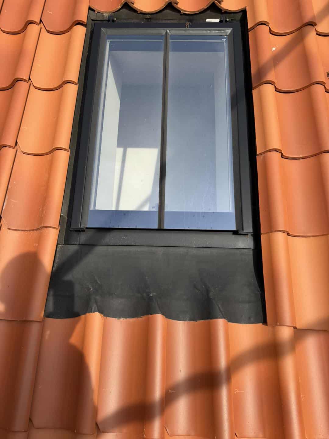 Billedet viser en moderne vinduesudskiftning på en tagterrasse med røde teglsten.