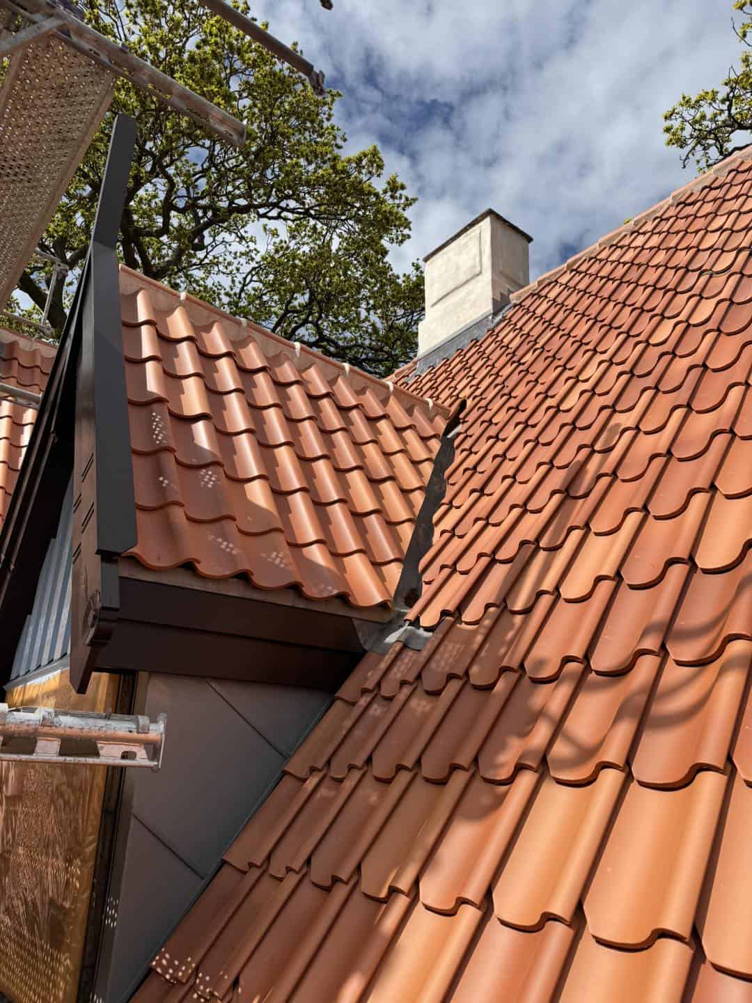 Tagdækning med klassiske røde teglsten på tag med fokus på arkitektur og detaljer.
