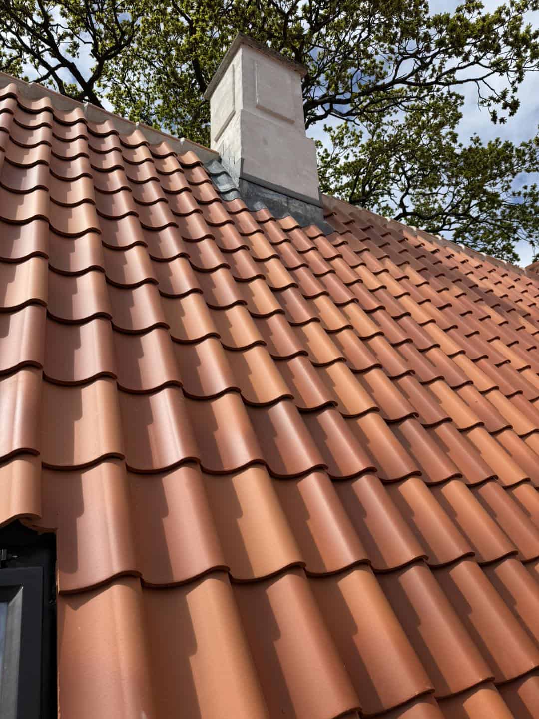 Rødt tag med tagrender og skorsten, fokus på arkitektur og detaljer.