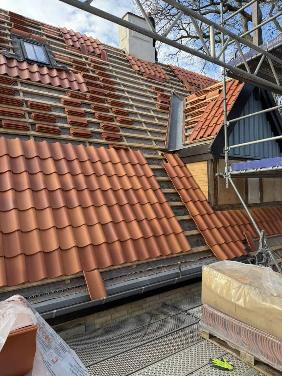 Ny tagdækning med røde teglsten, der fremhæver arkitekturens detaljer og håndværk.